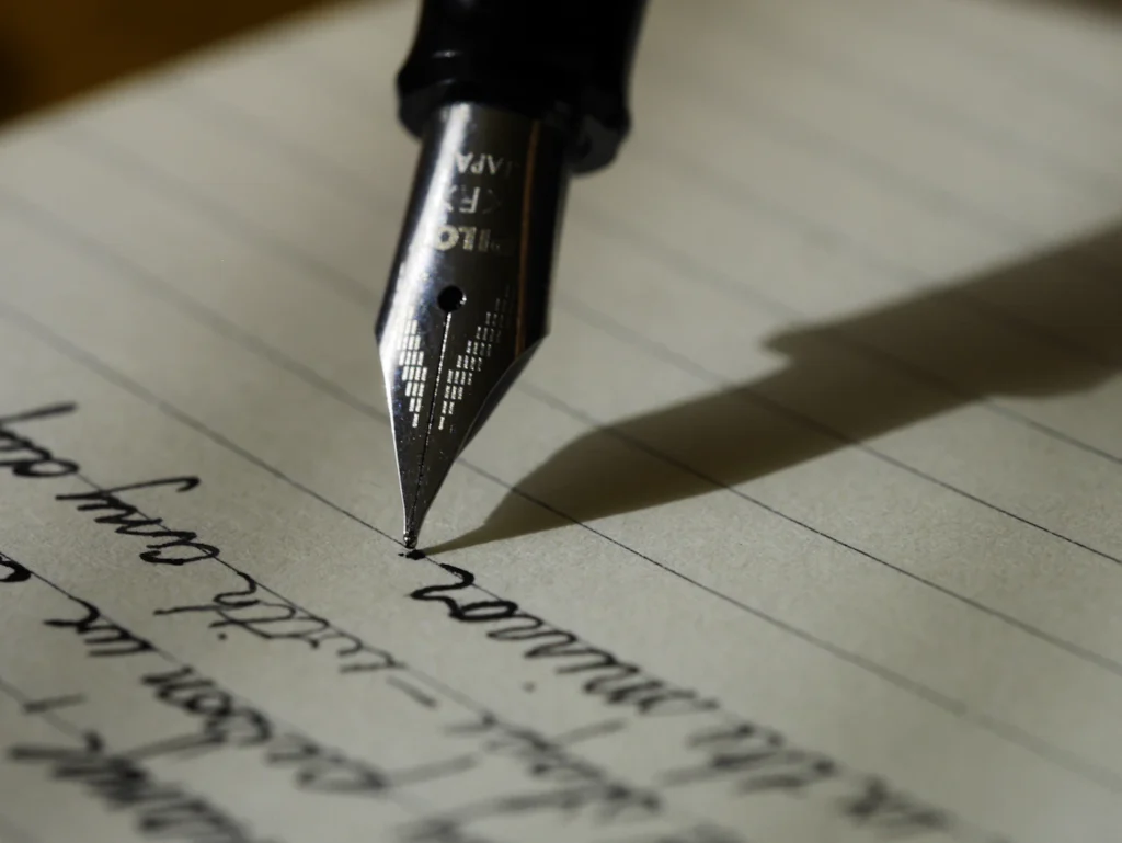 A fountain pen writing in a lined notebook